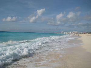 Waves crash onto a white sand beach in Cancun, Mexico. 