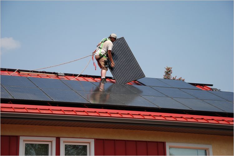 workers installing solar panels on house roof