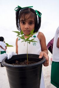 A young girl prepares to plant a tree during a 10/10/10 global work party event in the Maldives.
