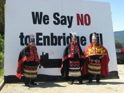 *Wetsuweten Chiefs stand in front of a billboard signalling their opposition to the Enbridge oilsands pipeline.