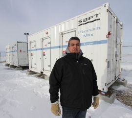 *Charlie Delorme in front of the two shipping containers that contain 400 kilowatts of batteries which are located right beneath the wind turbine. 