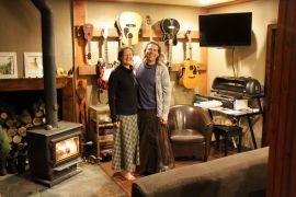 * The Taylor-Fayes in their living room of their straw bale home that is heated by wood and powered by solar and wind energy