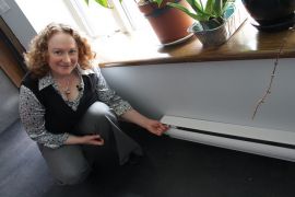 * Serena Kaba shows the electric baseboard heaters that are the second backup after a fireplace to their passive solar heated home.
