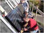 workers installing solar panels on house roof