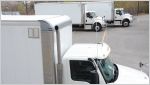 Three white freight trucks in parking lot