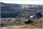 Oil sands mine site. Piles of dirt in a pit dug into the ground with excavators on site.