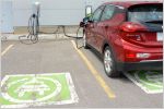 Electric car plugged into charger next to empty parking space