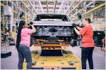Two women working on an electric Ford F-150 Lightning pickup truck at an assembly plant