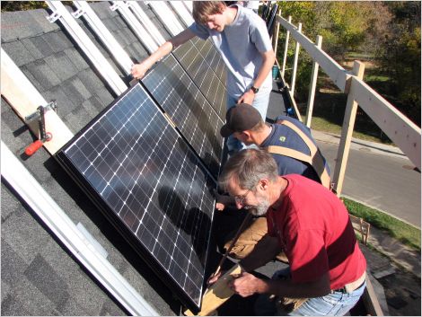 workers installing solar panels on house roof