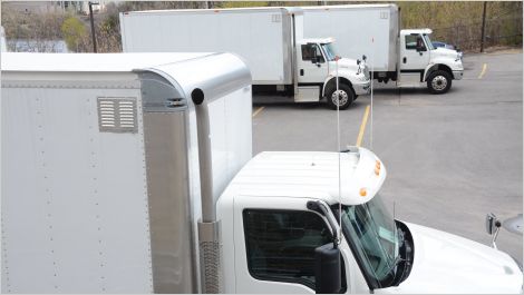 Three white freight trucks in parking lot