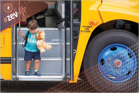 Small child with stuffed animals exiting electric school bus