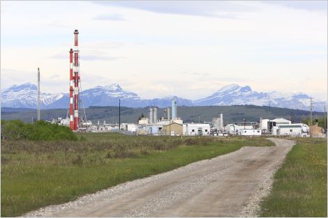 Road leading to a gas plant blocking the view of Alberta's mountains