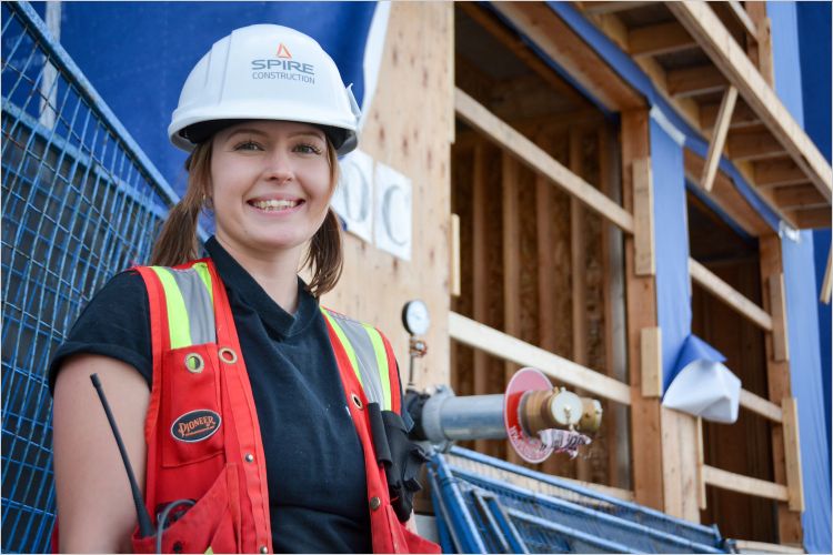 Woman in safety vest in front of Green building