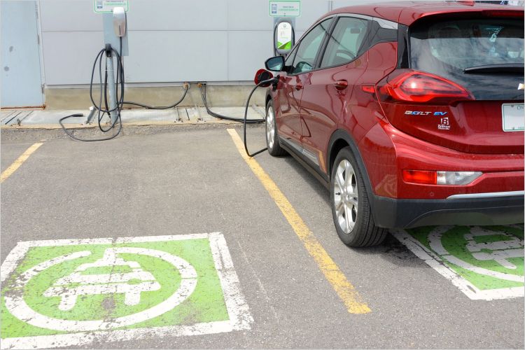 Electric car plugged into charger next to empty parking space