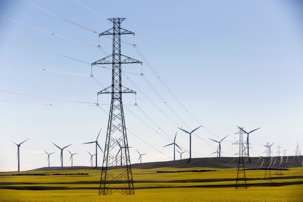 Power supply towers in the middle of a yellow canola field in bloom near Cowley and Pincher Creek, Alberta, Canada.