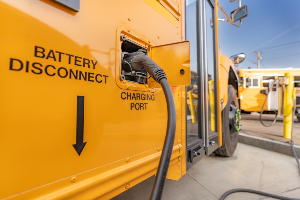 Yellow electric school bus plugged in at a charging station