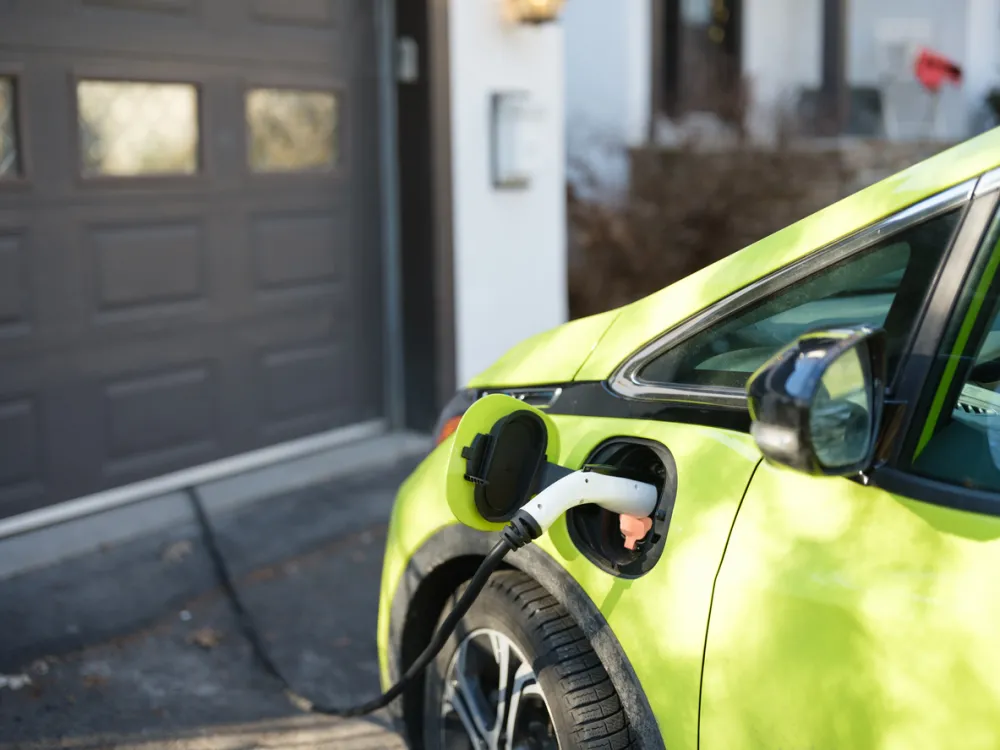 Electric car charging near house garage in suburbs
