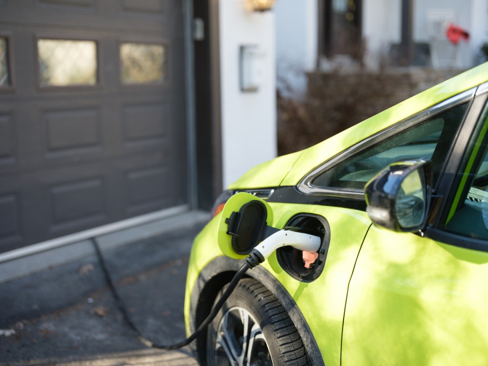 Electric car charging near house garage in suburbs