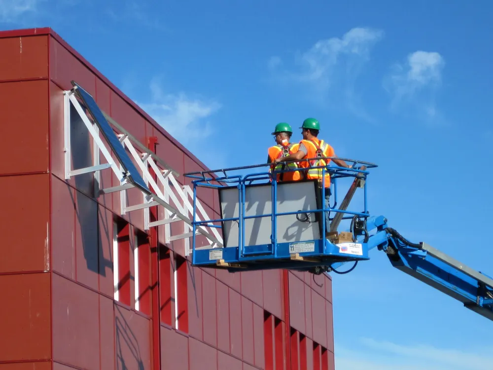 Labourers instal solar panels on community building 