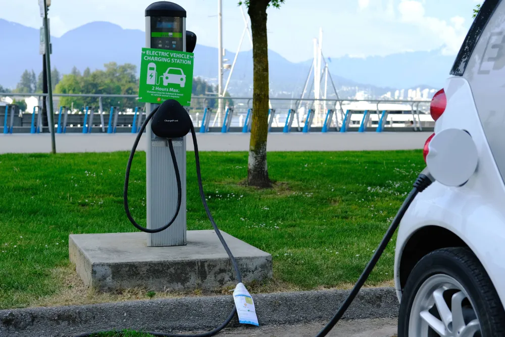 Electric vehicle plugged at a public charging space near a waterfront in British Columbia