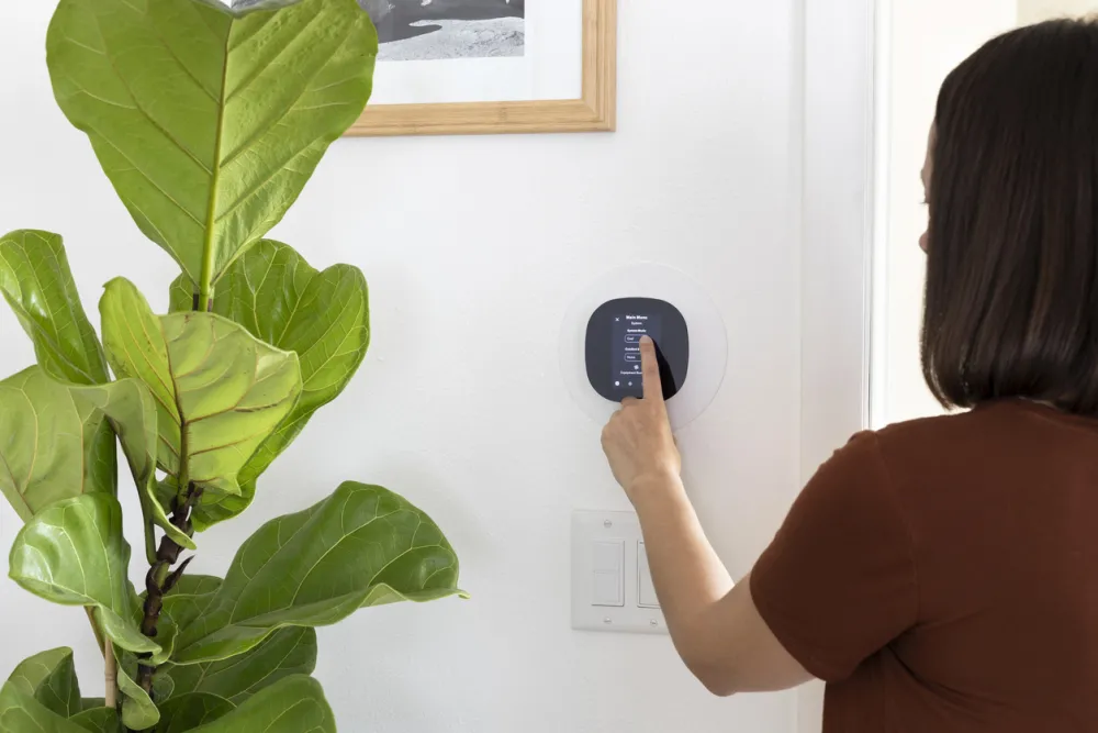 Woman adjusting smart thermostat