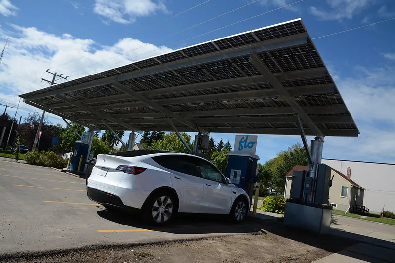 Wide view of an electric car connected to a charging station at a public EV charging site