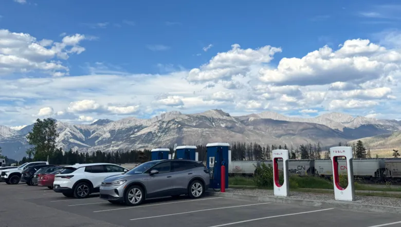 A Volkswagen ID.4 charging at Tesla Superchargers in Jasper, Alberta, with Rocky Mountains in the background.