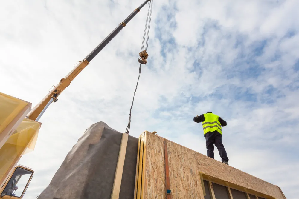 Builder with crane installing an insulated panel