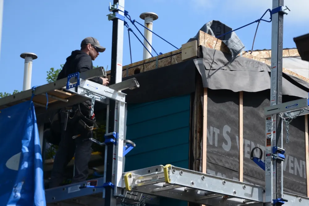 Worker on scaffolding retrofitting multifamily house