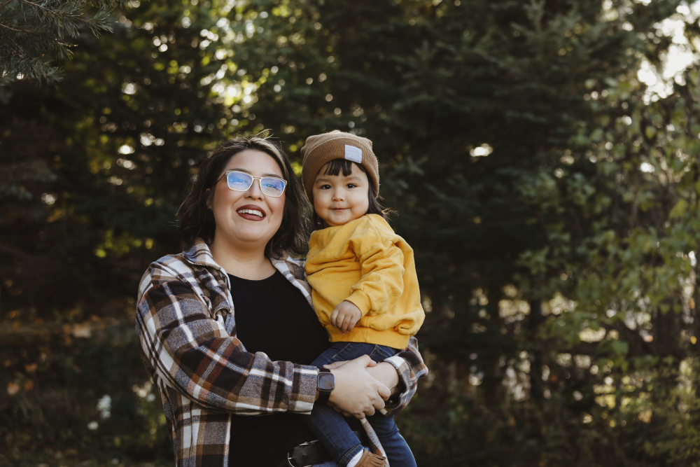 Indigenous woman holds a toddler outdoors 