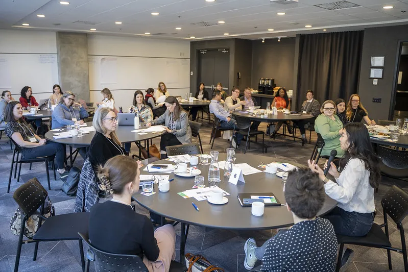 People seated around round tables in a workshop, engaged in discussion