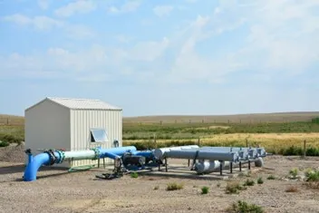 Oil and gas equipment in a field next to a small building
