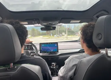 View from the back seat of a Volkswagen ID.4, showing the driver and front passenger travelling on a road.