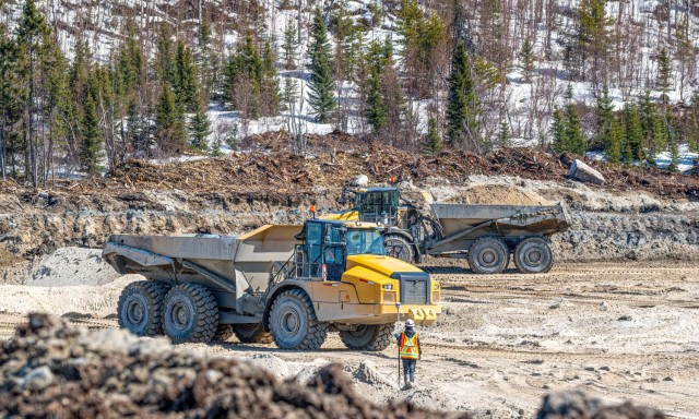 Worker standing in front of a large construction vehicle at a mining site