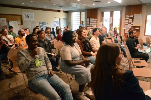 Pembina staff sit in a room, laughing while they watch a presentation. 