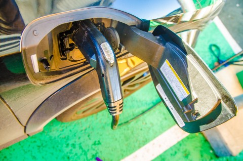 close-up on electrical plug in car being charged during day