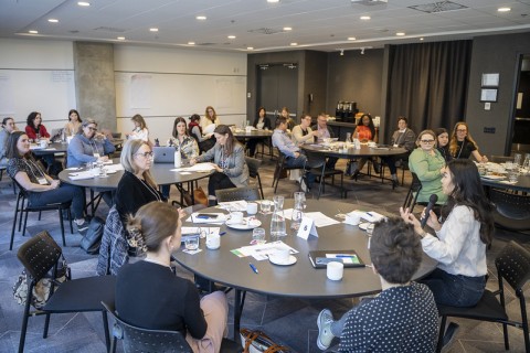 People seated around round tables in a workshop, engaged in discussion