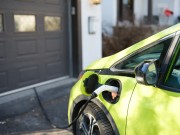 Electric car charging near house garage in suburbs