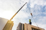 Roofer builder worker with crane installing structural insulated panels