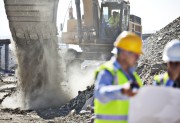Workers at mining site with a digger in the background 