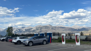 A Volkswagen ID.4 charging at Tesla Superchargers in Jasper, Alberta, with Rocky Mountains in the background.
