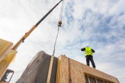 Builder with crane installing an insulated panel