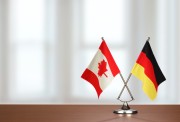Canada and Germany flags crossed on a desk