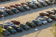 Large parking lot of car dealer with many brand new cars parked for sale