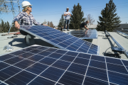 Workers installing solar panels on a residential home roof. 